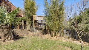 A fenced outdoor area with a wooden structure, stone steps, and sparse vegetation. - Sevierville Home: Lookout Deck, 10 Mi to Dollywood (Sevierville)