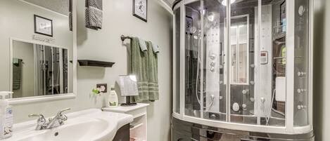 A bathroom with a sink, mirror, towel rack, shower enclosure, and a vanity.