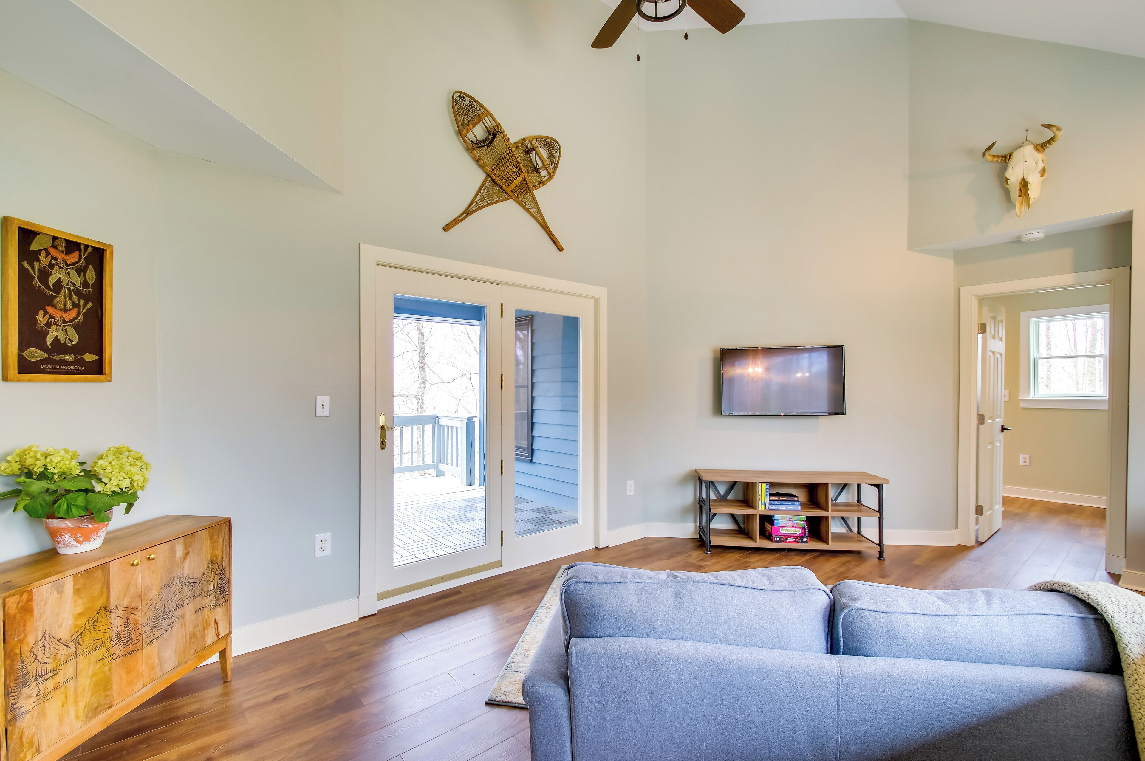 Una sala de estar con un sofá azul, piso de madera, un televisor y un elemento decorativo en la pared.