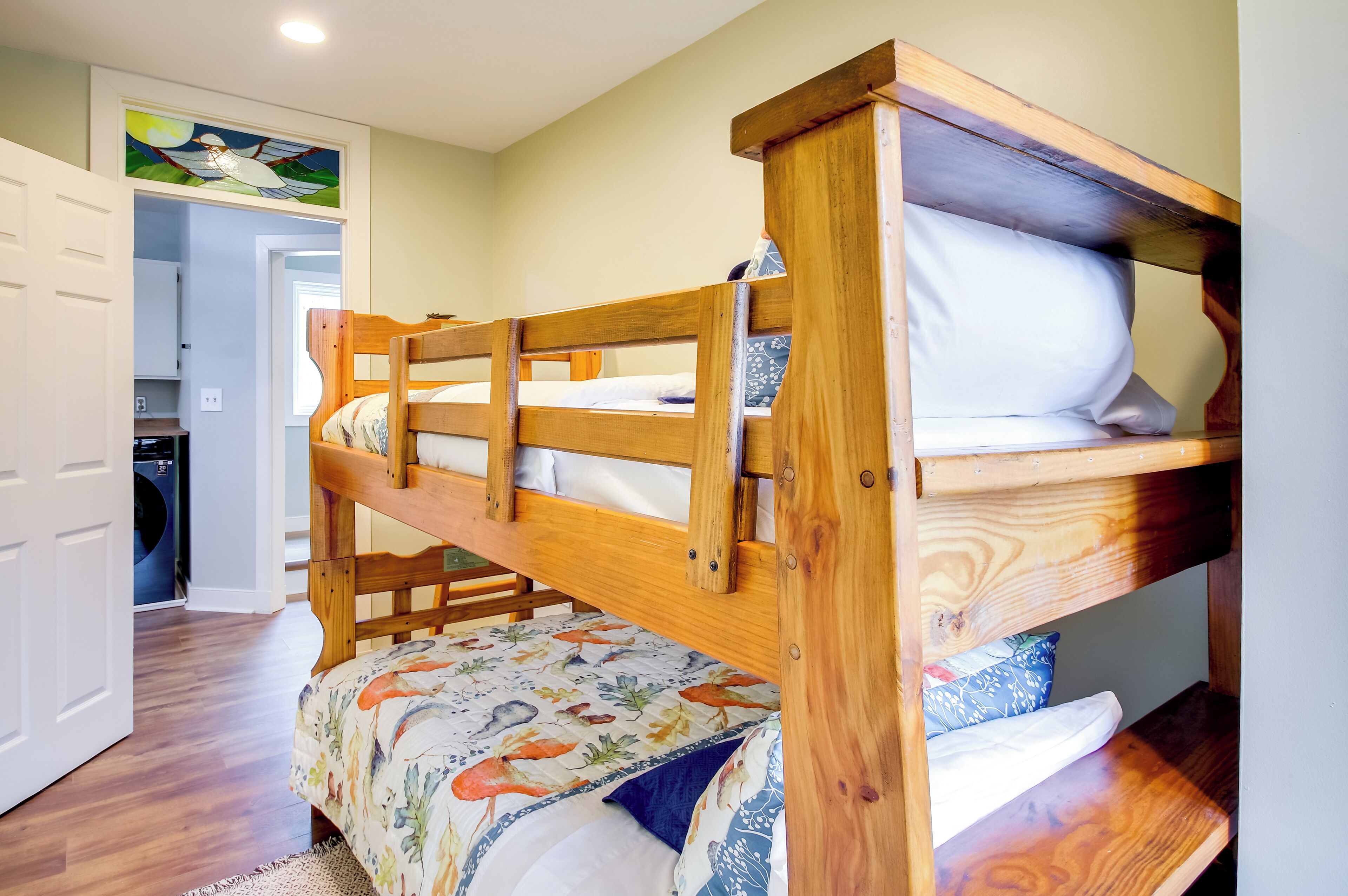 A bunk bed with a floral bedspread, wooden headboard, and a small table.
