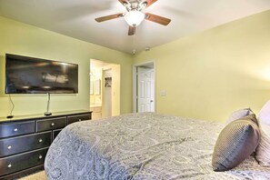 A bedroom with a bed, a ceiling fan, a TV on a dresser, and a door leading to another room. - Lakefront Ozarks Condo By Golf & Restaurants! (Lake Ozark)