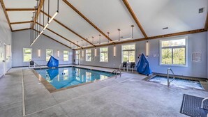 Une piscine intérieure dotée d’un plafond en bois et de grandes fenêtres.