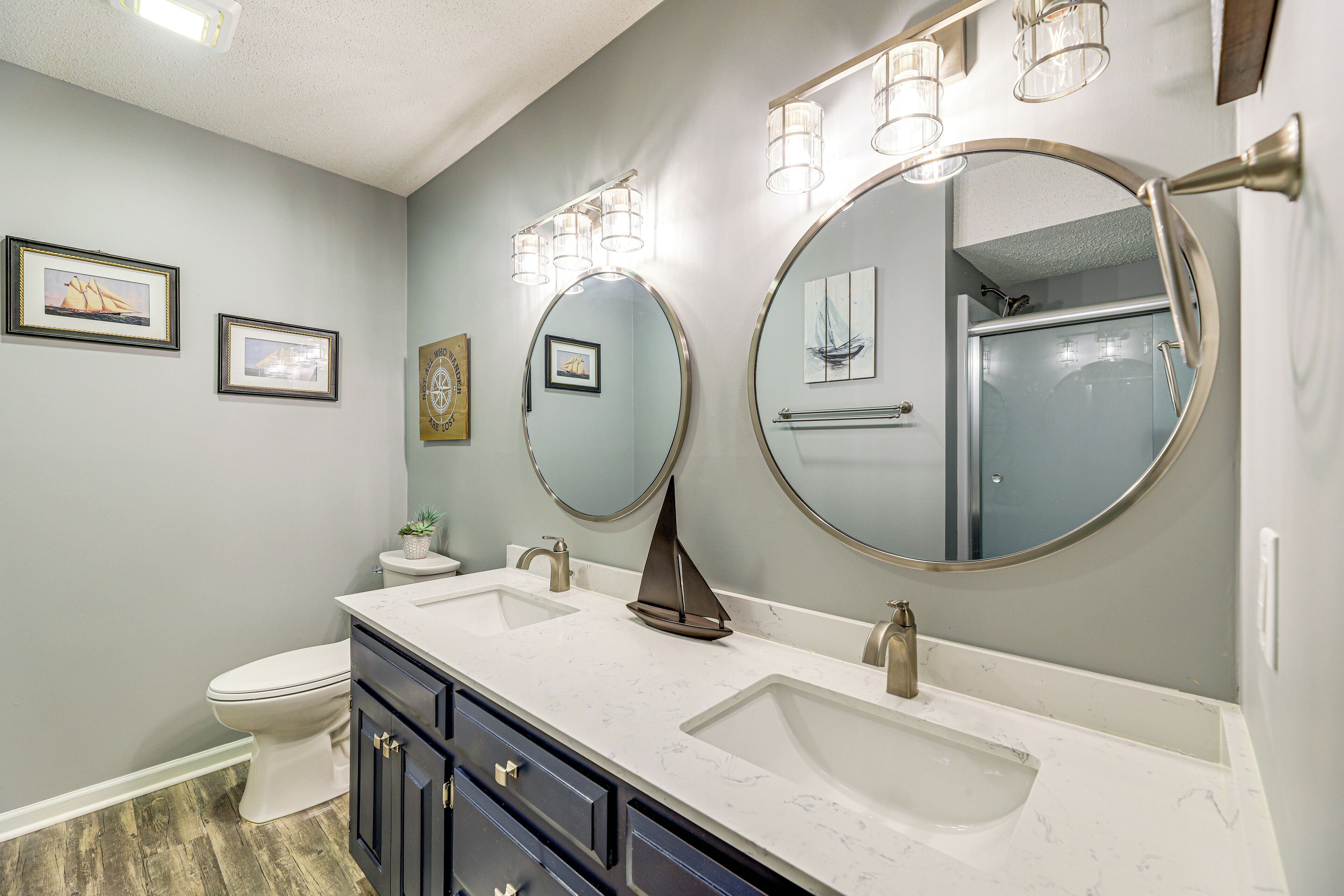 A bathroom with two sinks, a toilet, and a large mirror.
