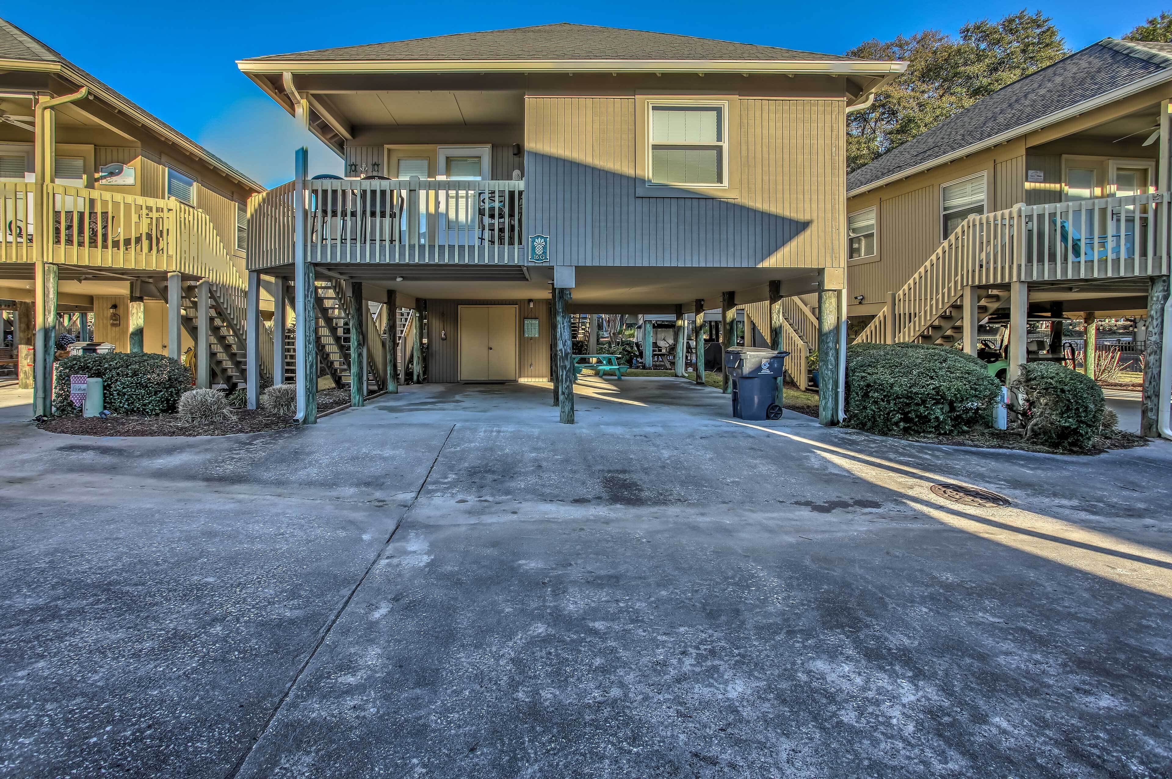 A multi-story building with a covered walkway, outdoor seating, and a small parking area.