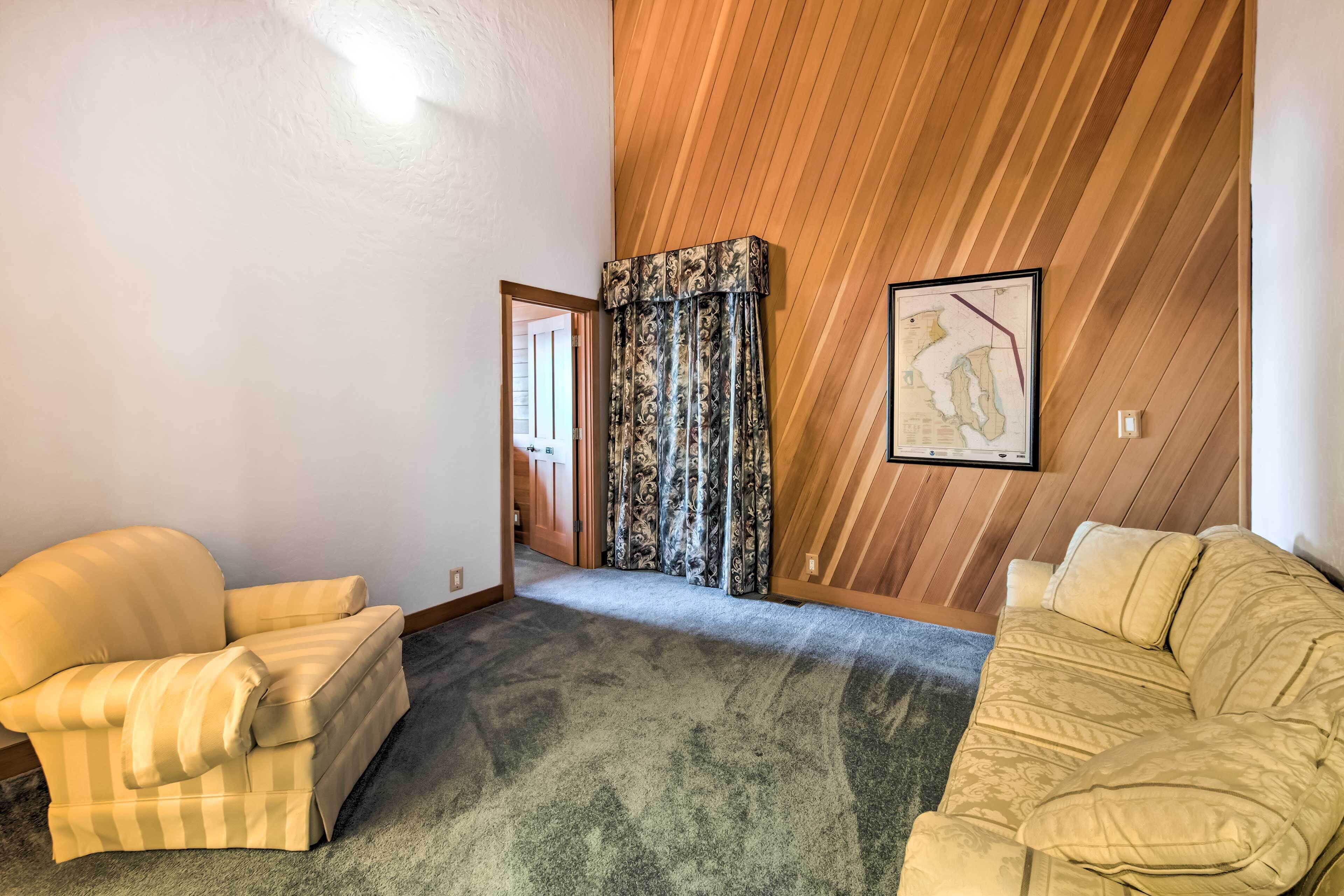 A room with two beige sofas, a patterned curtain, a framed map on the wall, and a wooden ceiling.