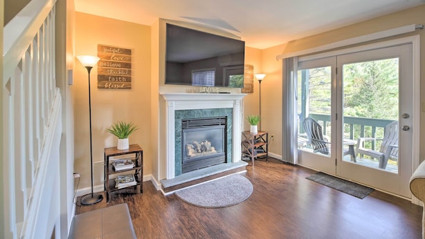 A living room with a fireplace, a staircase, and a view through a glass door. - Lake Placid Home ~ 9 Mi to Whiteface Mtn! (Lake Placid)