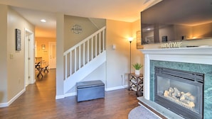 A living room with a fireplace, a staircase, and a dining area. - Lake Placid Home ~ 9 Mi to Whiteface Mtn! (Lake Placid)