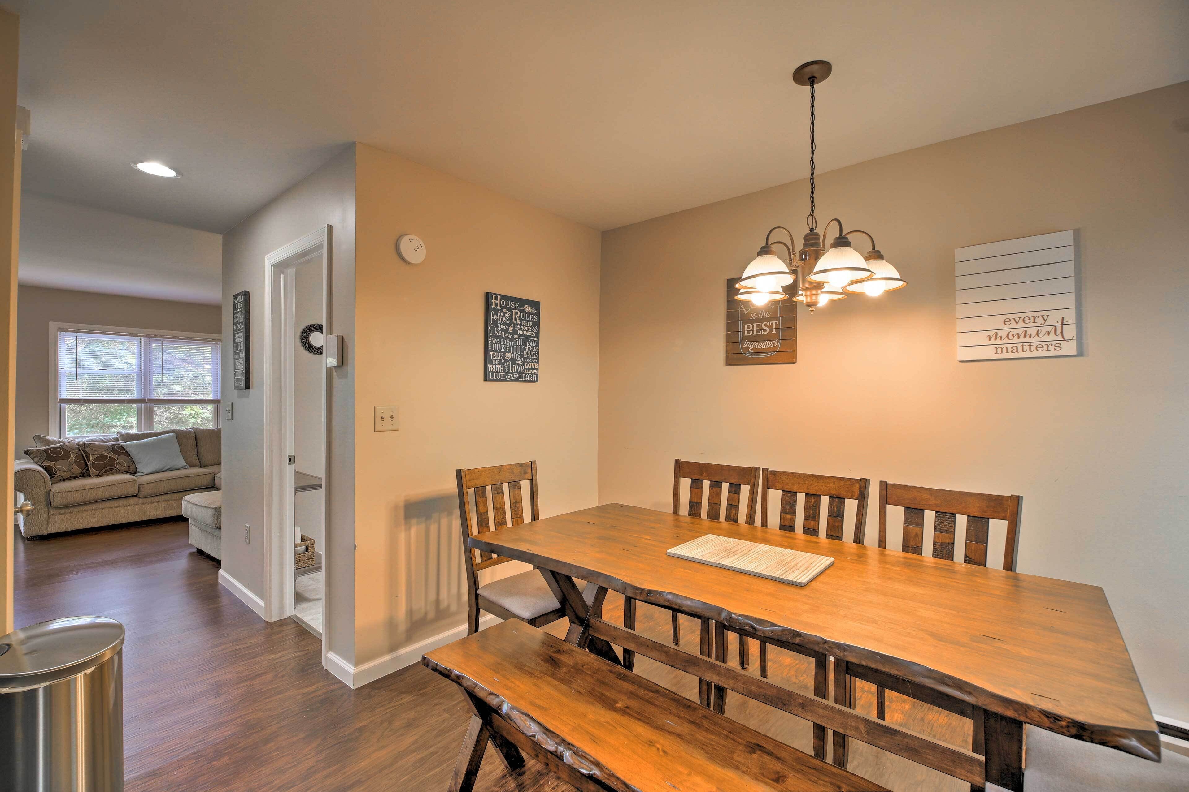 A dining area with a wooden table and chairs, a chandelier, and wall decorations.