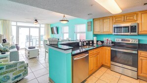 A kitchen with wooden cabinets, a stainless steel microwave, and a dishwasher. - Myrtle Beachfront Bliss: Pools, Views & Skywheel! (Myrtle Beach)