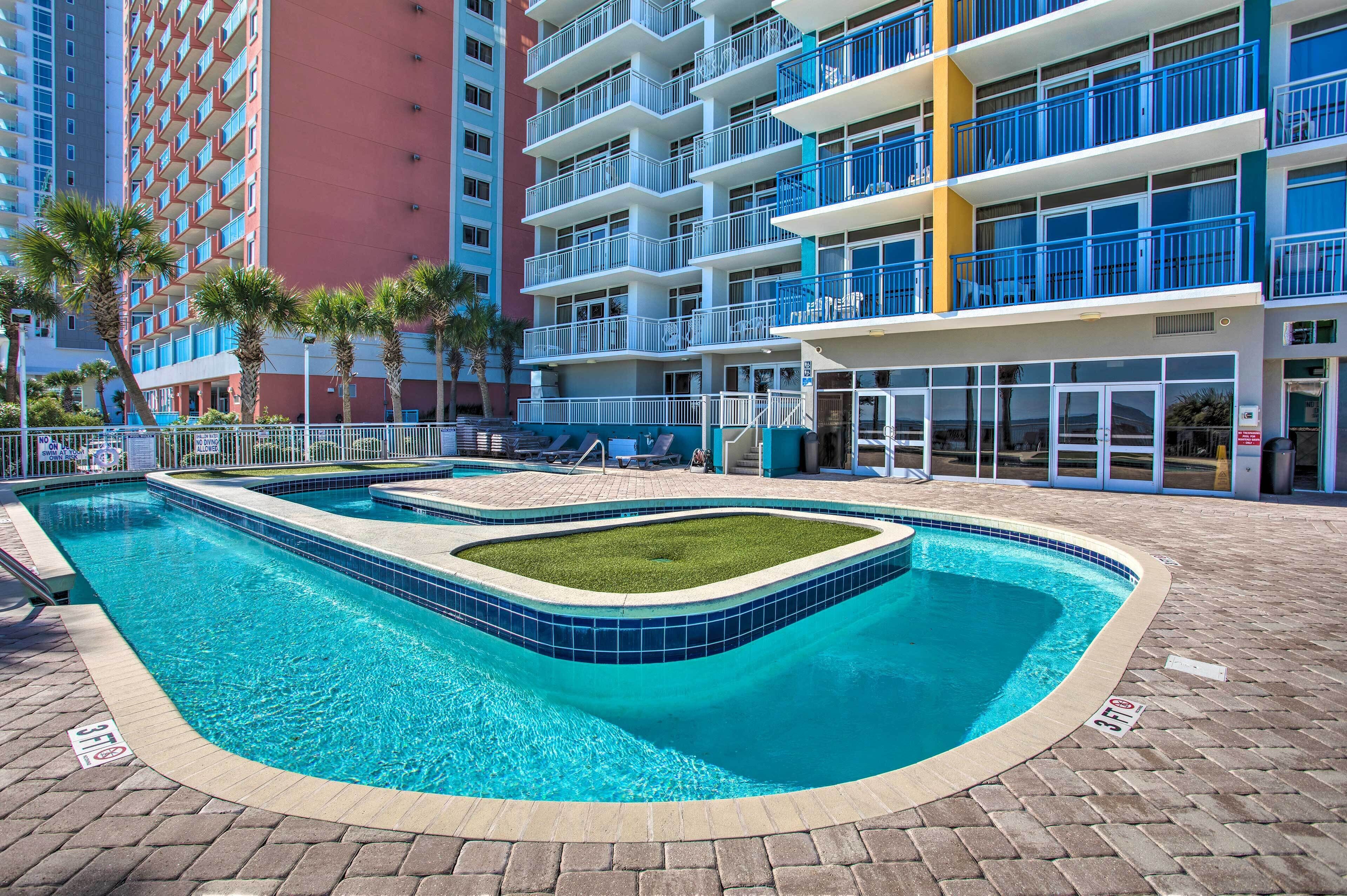 A swimming pool with a tiled edge and a grassy area in the center, surrounded by a brick walkway.