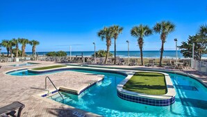A pool area with multiple swimming pools, palm trees, and a view of the ocean. - Myrtle Beachfront Bliss: Pools, Views & Skywheel! (Myrtle Beach)