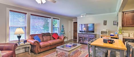 A living room with a leather couch, a coffee table, and a TV in the background.
