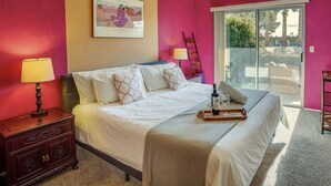 A bedroom with a bed, a nightstand, a lamp, a framed picture, and a sliding glass door to a balcony. - Borrego Springs Vacation Rental: Patio & Gas Grill (Borrego Springs)