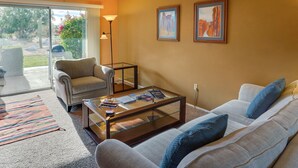 A living room with a sofa, armchair, glass coffee table, and a lamp. There are two framed pictures on the wall. - Borrego Springs Vacation Rental: Patio & Gas Grill (Borrego Springs)