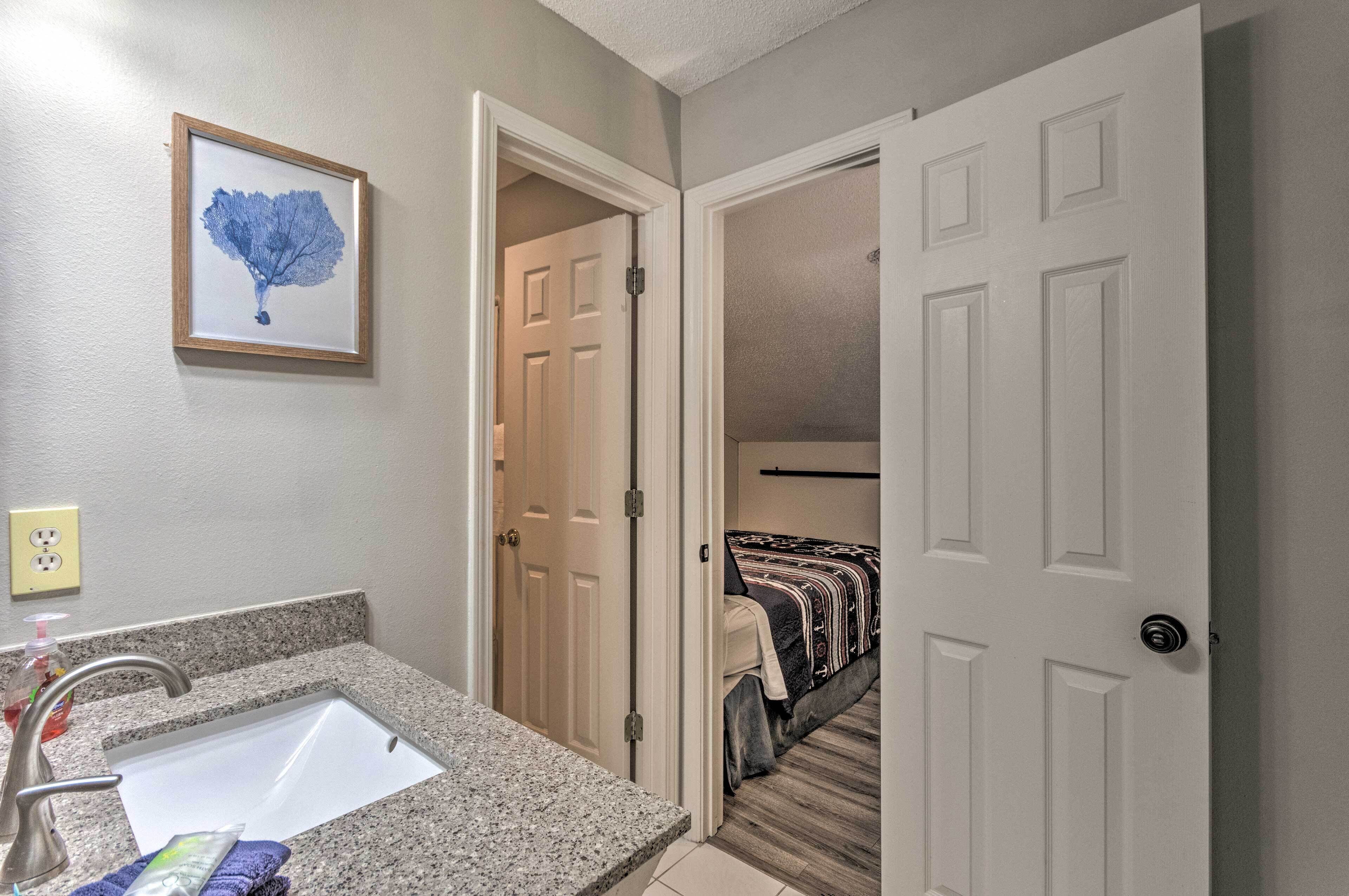 A bathroom with a granite countertop, a sink, and a framed artwork on the wall.
