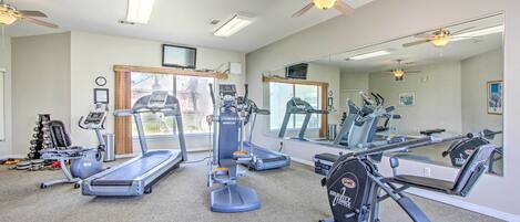 A gym with treadmills, elliptical machines, and a weight bench.