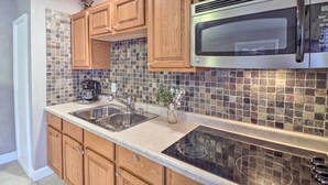 A kitchen with wooden cabinets, a stainless steel sink, a microwave, and a tiled backsplash. - Riverside Studio: Trophy Trout Fishing On-site (Lakeview)