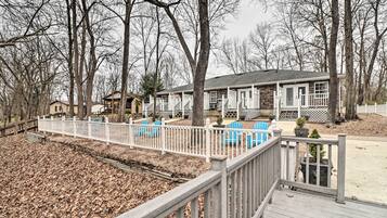 A residential property with a wooden deck, outdoor seating, and a fenced yard.