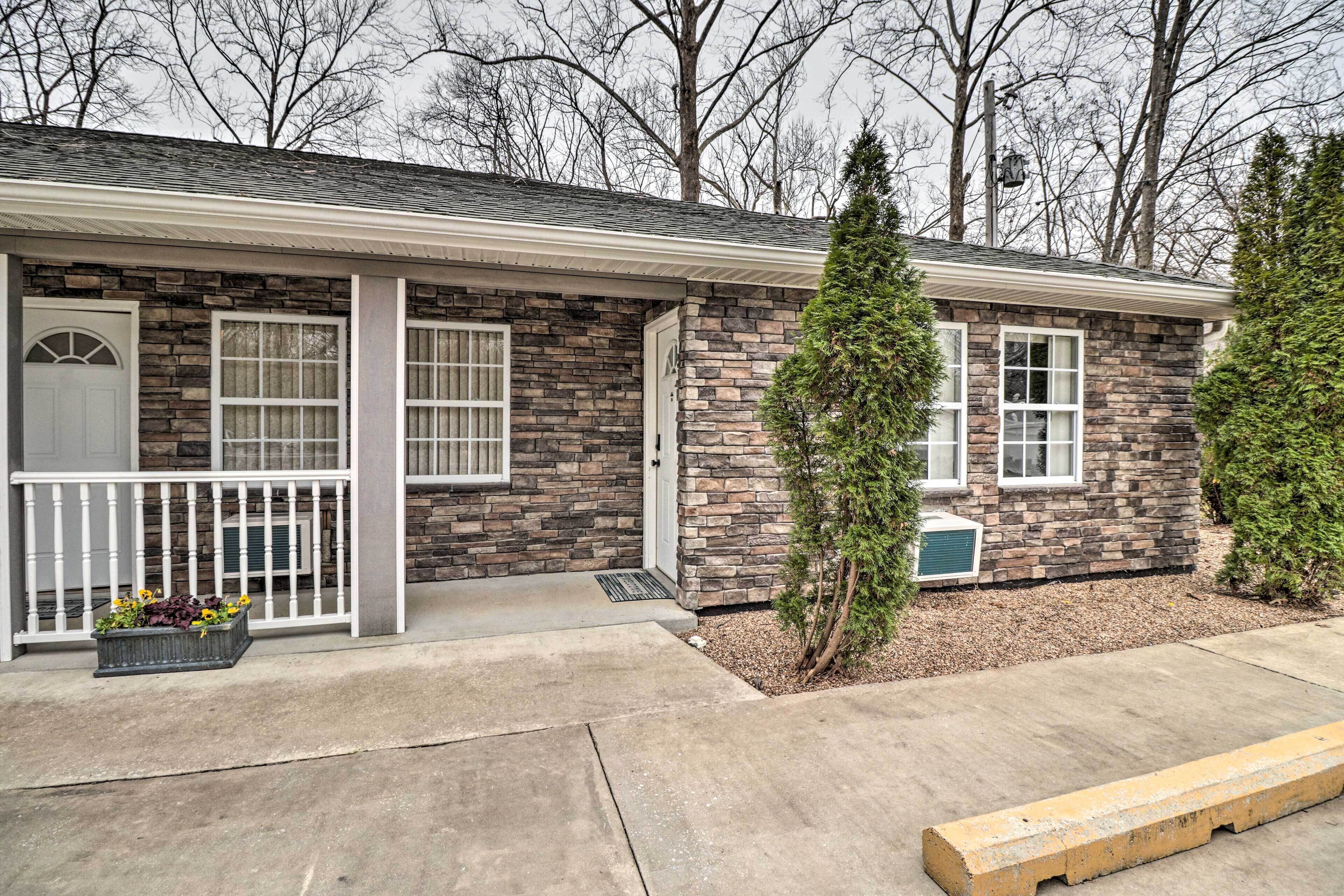 A two-story stone house with a front porch, a small front yard, and a wooden bench.