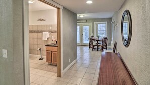 A spacious hallway with a wooden dining table and chairs, a kitchen area with a tiled backsplash, and a large mirror on the wall. - Riverside Studio: Trophy Trout Fishing On-site (Lakeview)