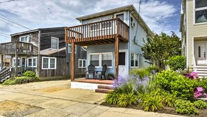 A two-story house with a balcony, a front porch with chairs, and a garden with various plants.