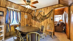 A wooden-paneled room with a round table and chairs, a ceiling fan, and a hammock.
