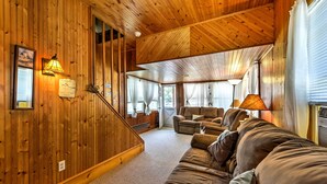 A wooden interior with a sofa, a lamp, and a staircase.