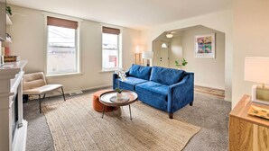 A living room with a blue sofa, a round coffee table, a beige armchair, and a small orange ottoman. - Cincinnati Vacation Rental: 6 Mi to Downtown! (Cincinnati)
