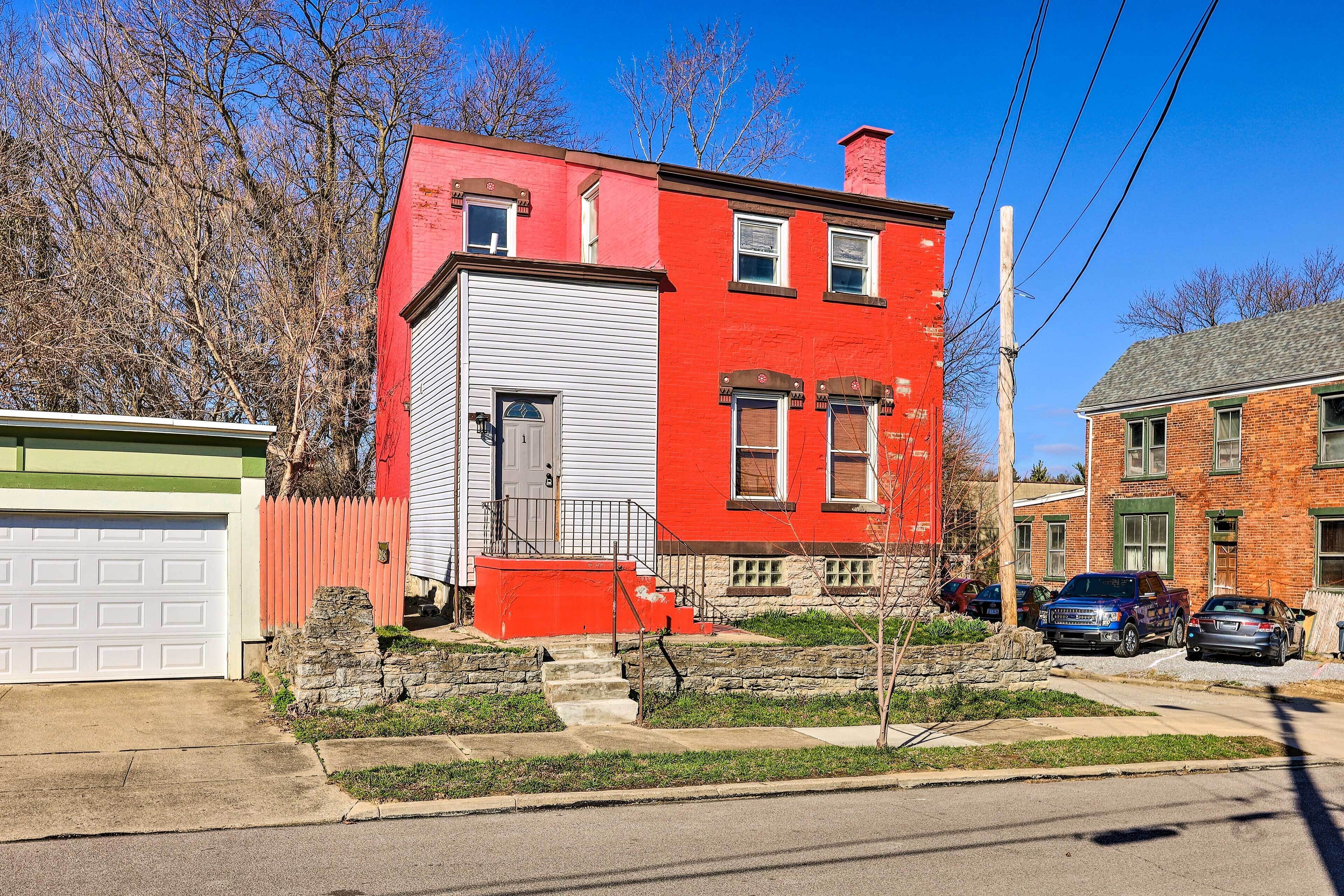 A red and white two-story house with a garage, a stone staircase, and a small front yard.