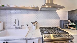 A modern kitchen with a stainless steel stove, white tiled backsplash, and a coffee machine. - Cincinnati Vacation Rental: 6 Mi to Downtown! (Cincinnati)