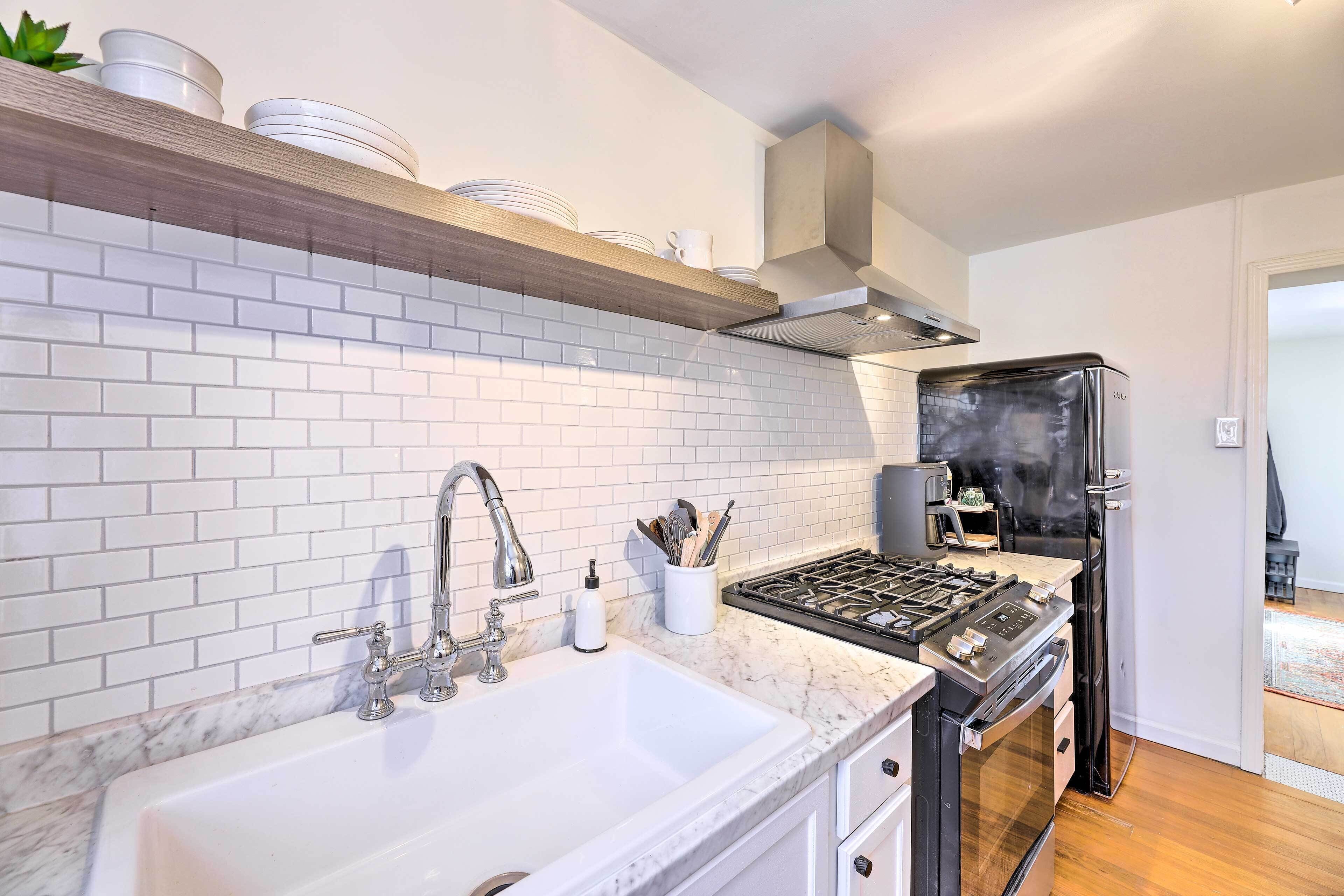 Una cocina moderna con baldosas blancas tipo metro, un lavamanos de acero inoxidable, horno empotrado y un refrigerador negro.