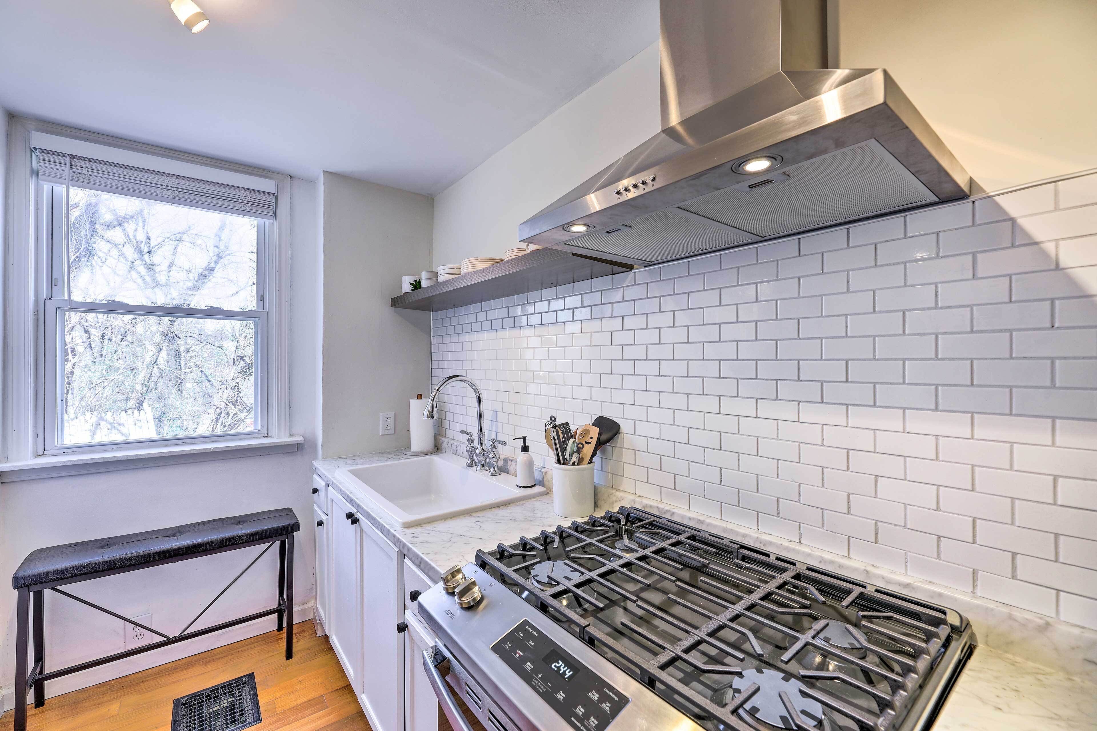 A modern kitchen with white subway tiles, stainless steel appliances, and a window with a view of trees.