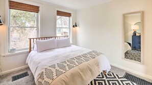 A neatly made bed with white linens, a patterned throw, and a window with a view of trees and a building outside. - Cincinnati Vacation Rental: 6 Mi to Downtown! (Cincinnati)