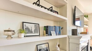 A bookshelf with framed pictures, books, and decorative items. - Cincinnati Vacation Rental: 6 Mi to Downtown! (Cincinnati)