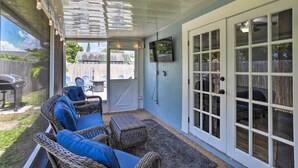 A covered patio with wicker furniture and a television mounted on the wall.