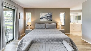 A modern bedroom with a large bed, a view to the outside, and a bathroom with a mirror and sink.