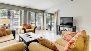 A living room with a sofa set, a coffee table, a TV, and a window with curtains.