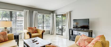 A living room with a sofa set, a coffee table, a TV, and a window with curtains.