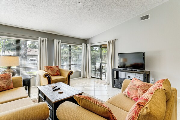 A living room with a sofa set, a coffee table, a TV, and a window with curtains. - Sarasota Villa w/ Pool Access ~ 4 Mi to Beach! (Sarasota)