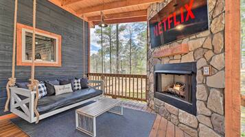 A cozy outdoor seating area with a swing, a stone fireplace, and a Netflix sign.