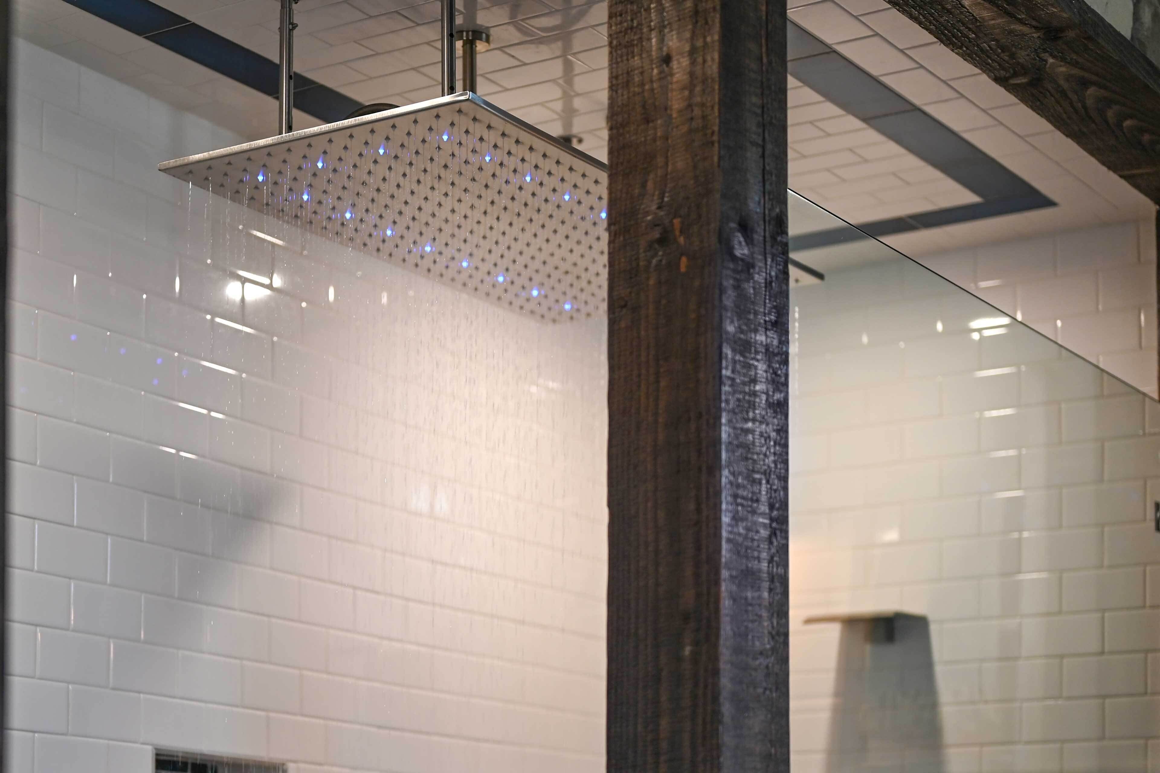 A modern shower with a perforated ceiling and a wooden column.