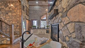 A stone-walled bathroom with a bathtub, a shower, and a window.