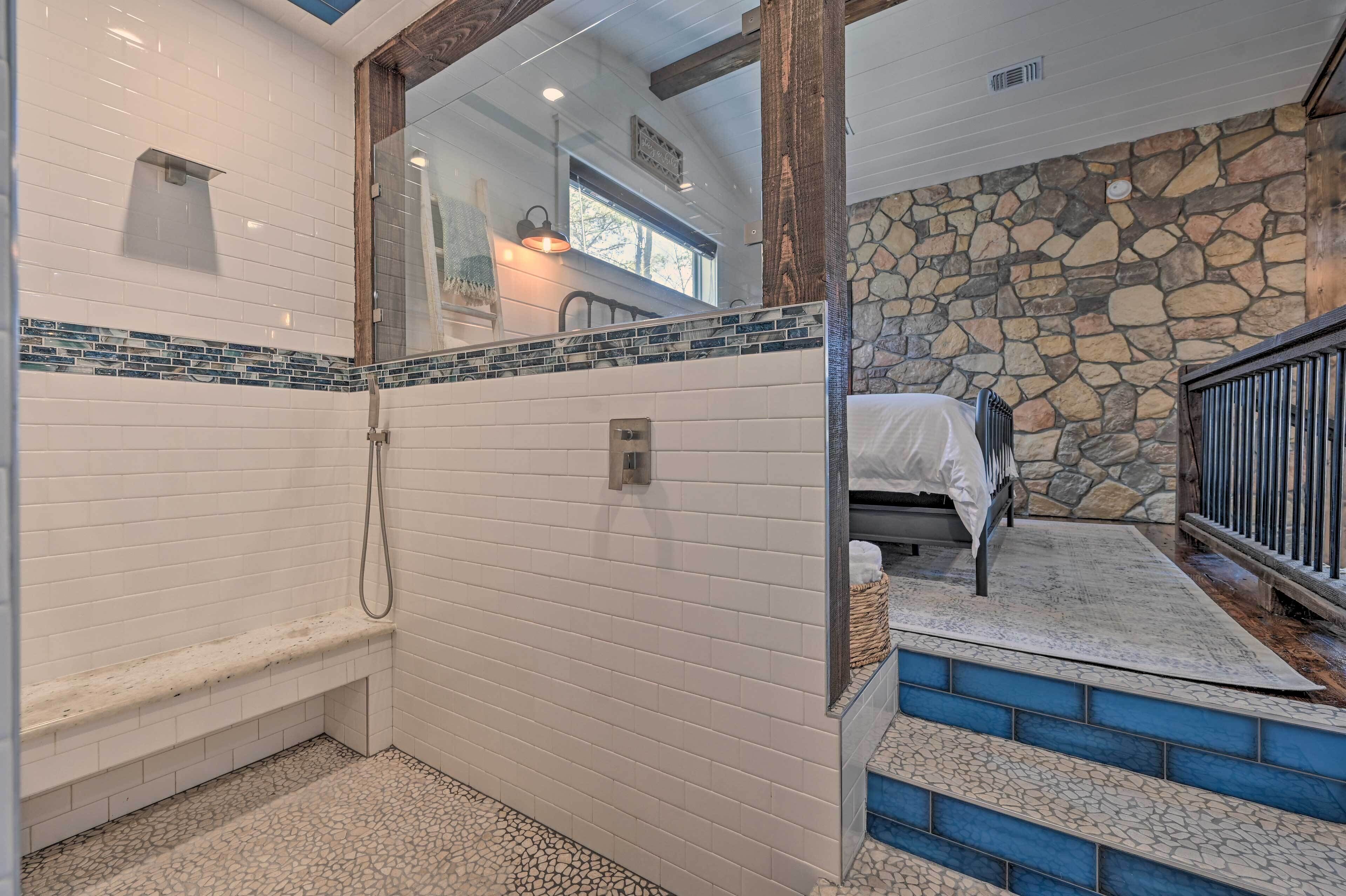 Baño con ducha, banco y pared de piedra.