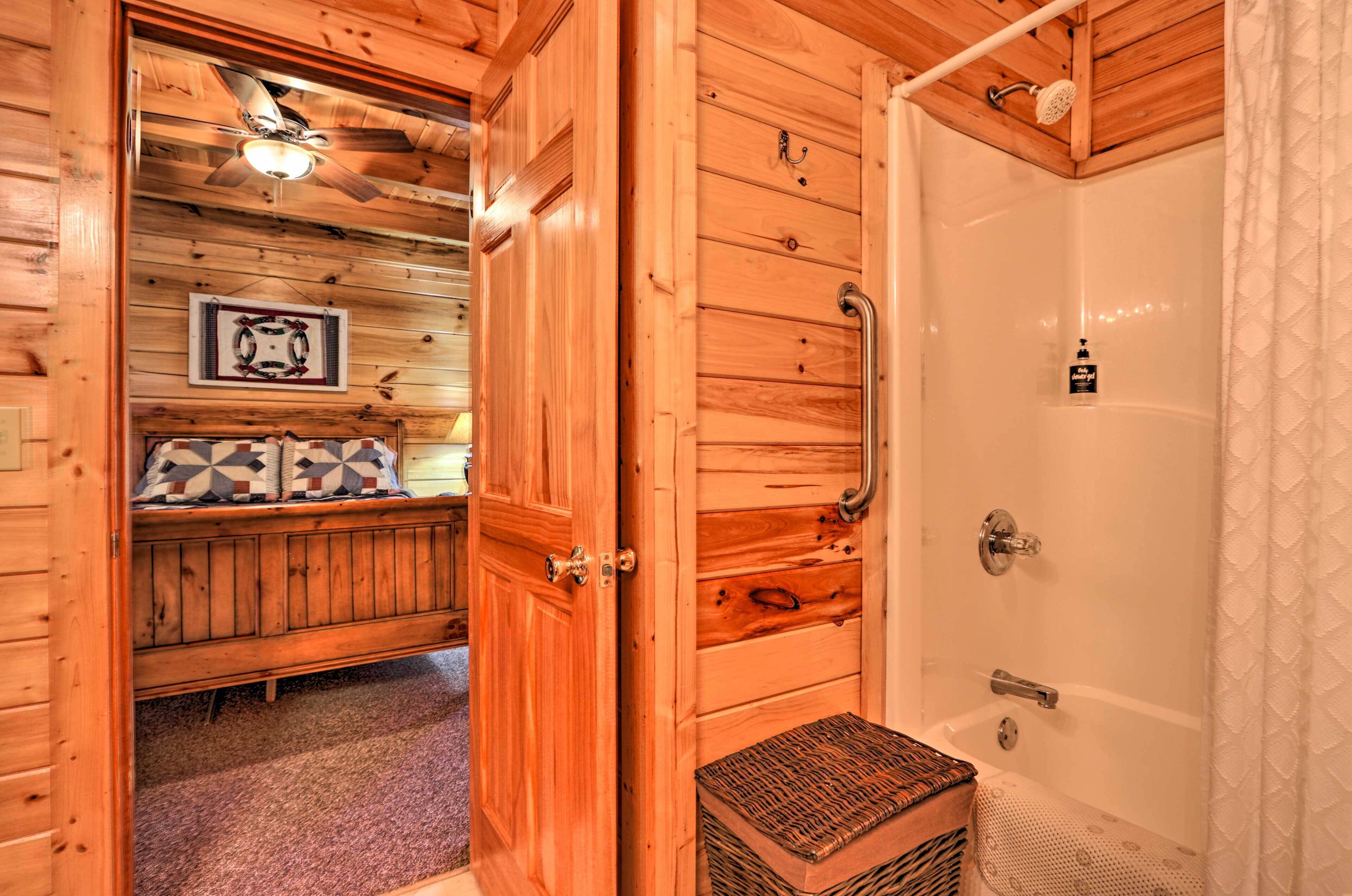 L’intérieur d’une cabane en bois comprend une douche, un banc agrémenté de coussins à motifs et un ventilateur de plafond.