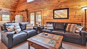 A cozy cabin interior with two leather sofas, a wooden coffee table, and a refrigerator.