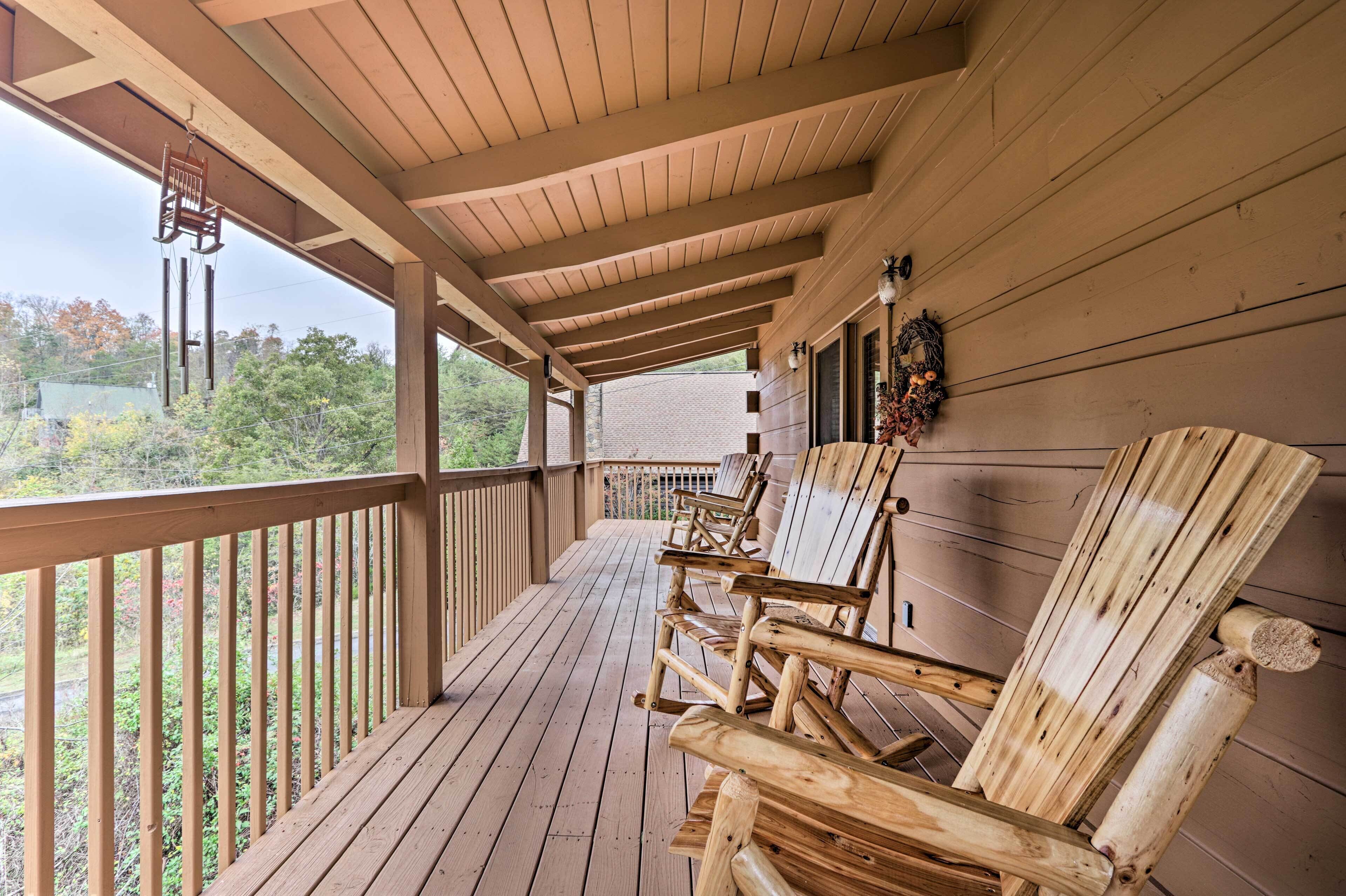 A wooden porch with rocking chairs, a hanging chair, and a wreath on the wall.