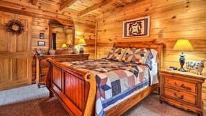 A wooden cabin bedroom with a bed, dresser, and nightstand.
