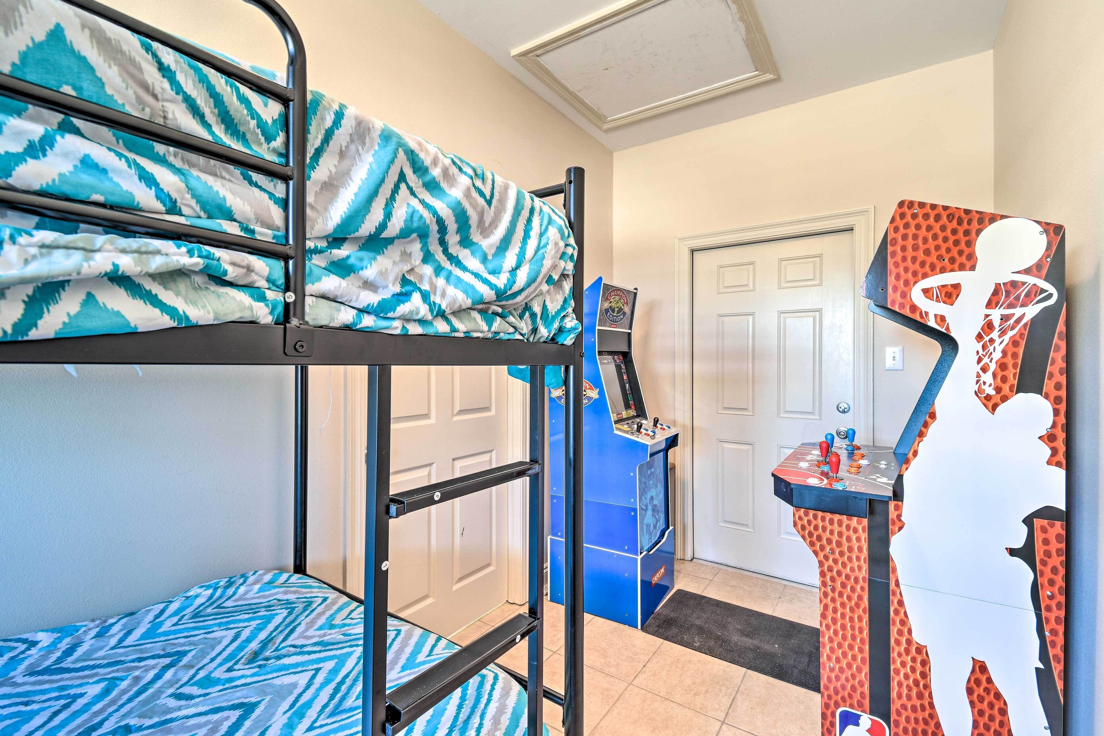 Un lit superposé avec une couvre-lit à motifs, un petit bureau décoré sur le thème du basketball et une porte visible au fond.