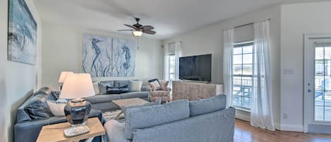 A modern living room with a sofa, a coffee table, a TV, and artwork on the walls.