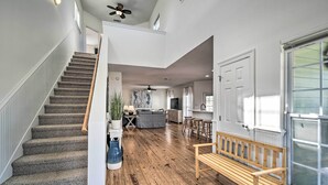 Amplia sala de estar con un banco de madera, una escalera y vista a la cocina.